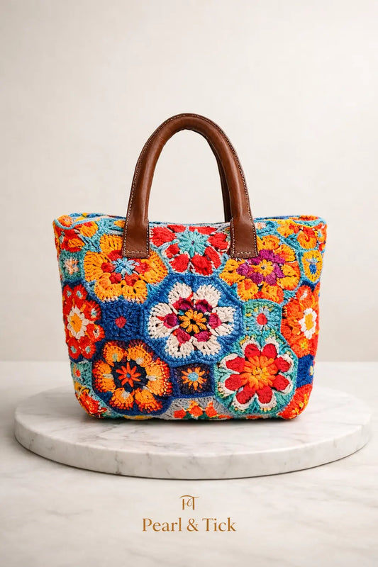 Colorful crochet bag with brown handles on a white background, featuring the brand 'Pearl & Tick'.