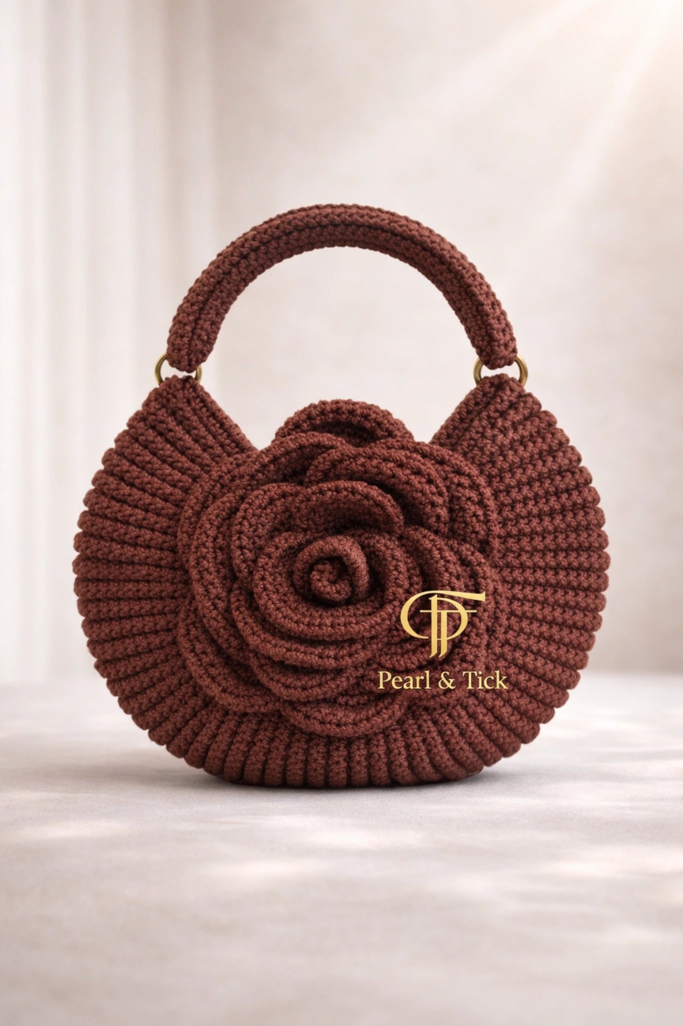 Borsa a mano all'uncinetto marrone con il logo «Pearl & Tick» su sfondo chiaro