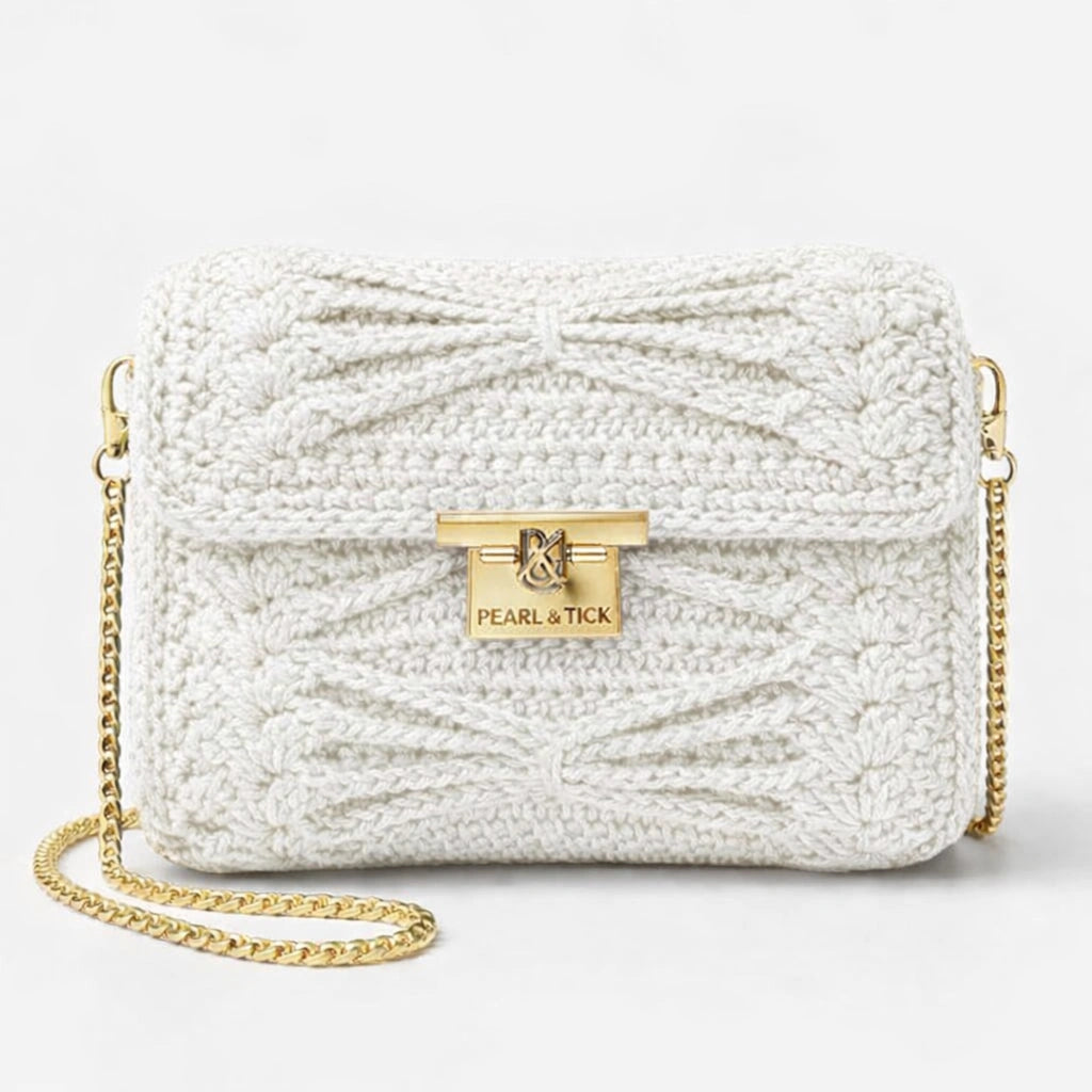 Sac à main tricoté blanc avec chaîne dorée et logo de la marque visible sur fond gris clair