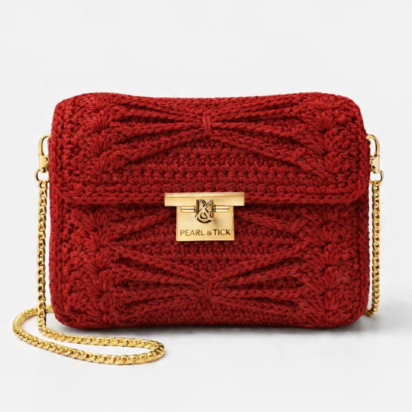 Sac à main tricoté rouge avec chaîne dorée et logo de la marque visible sur fond gris clair
