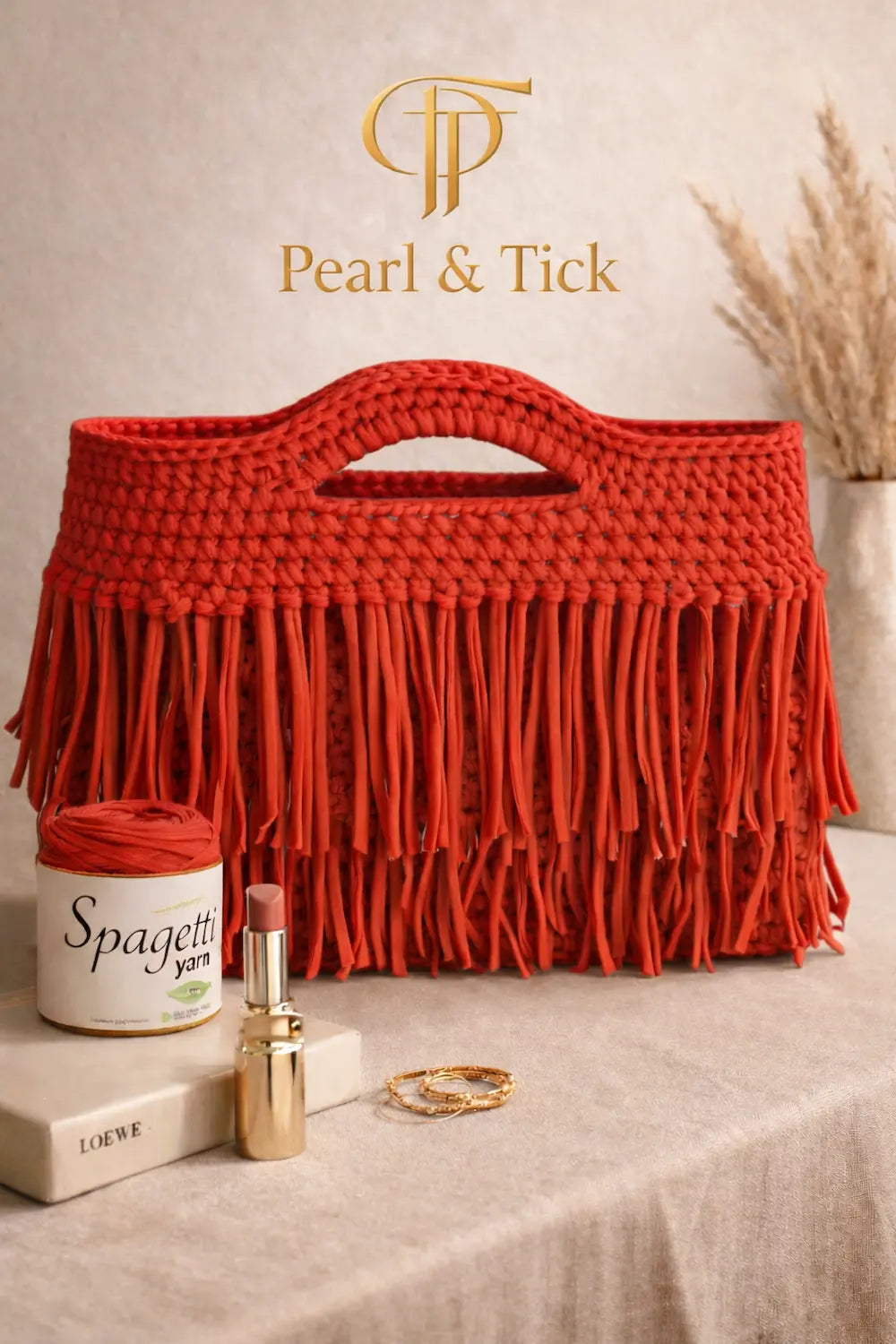 Red woven bag with fringe on a table with 'Pearl & Tick' branding.