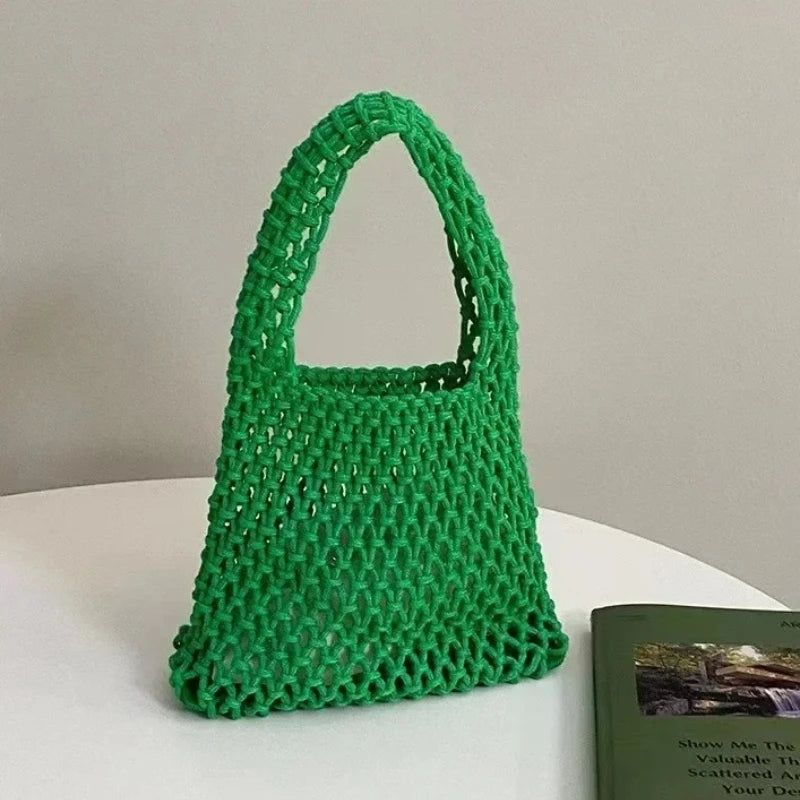 Sac à main tressé vert sur une surface blanche avec un livre en arrière-plan