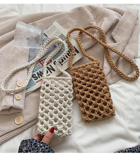 Due borse all'uncinetto, una bianca e una marrone, su un letto con un giornale e dei vestiti.