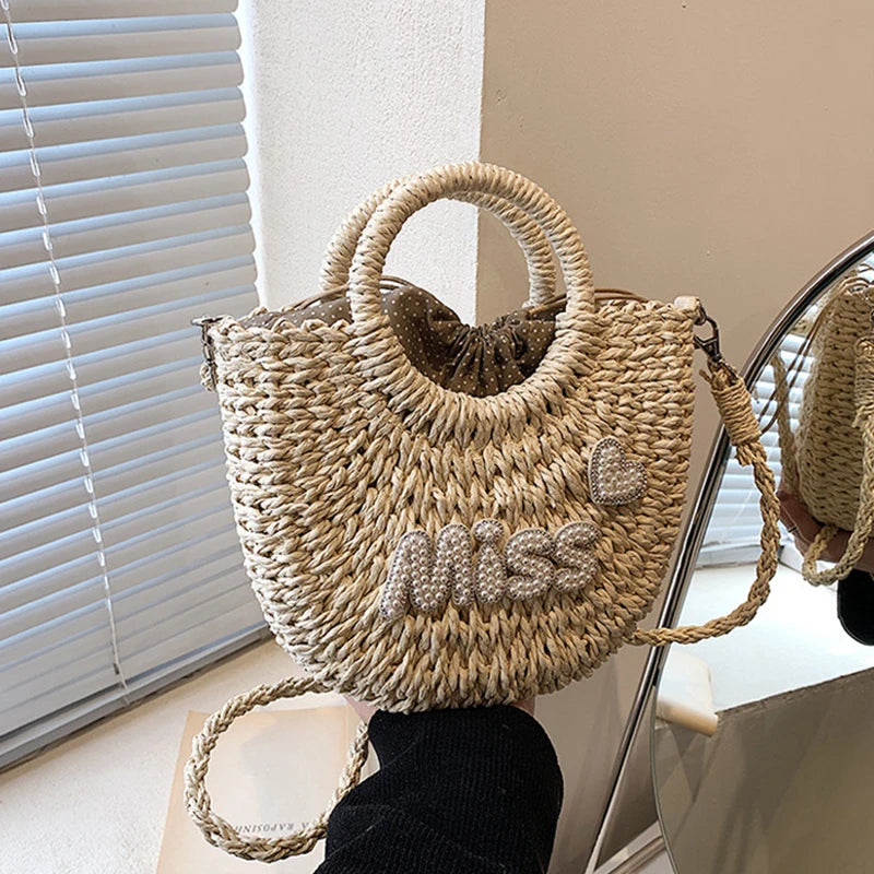 Woven handbag with 'MISS' text held by a person in a room with a window and mirror.