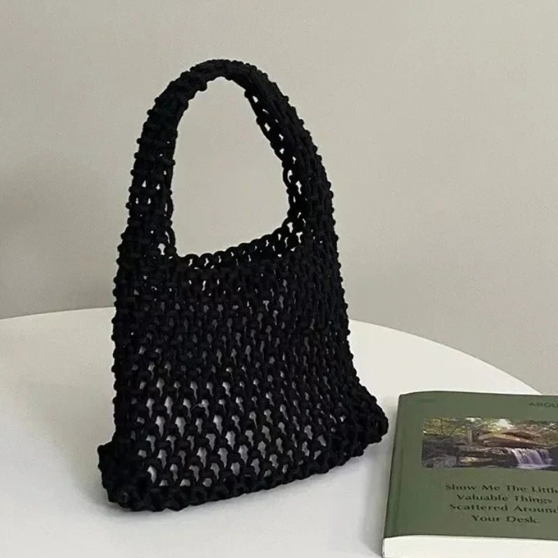 Sac à main tressé noir sur une surface blanche avec un arrière-plan flou
