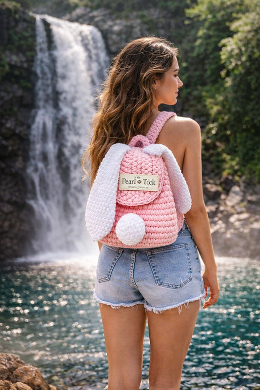Woman with a pink and white backpack standing in front of a waterfall