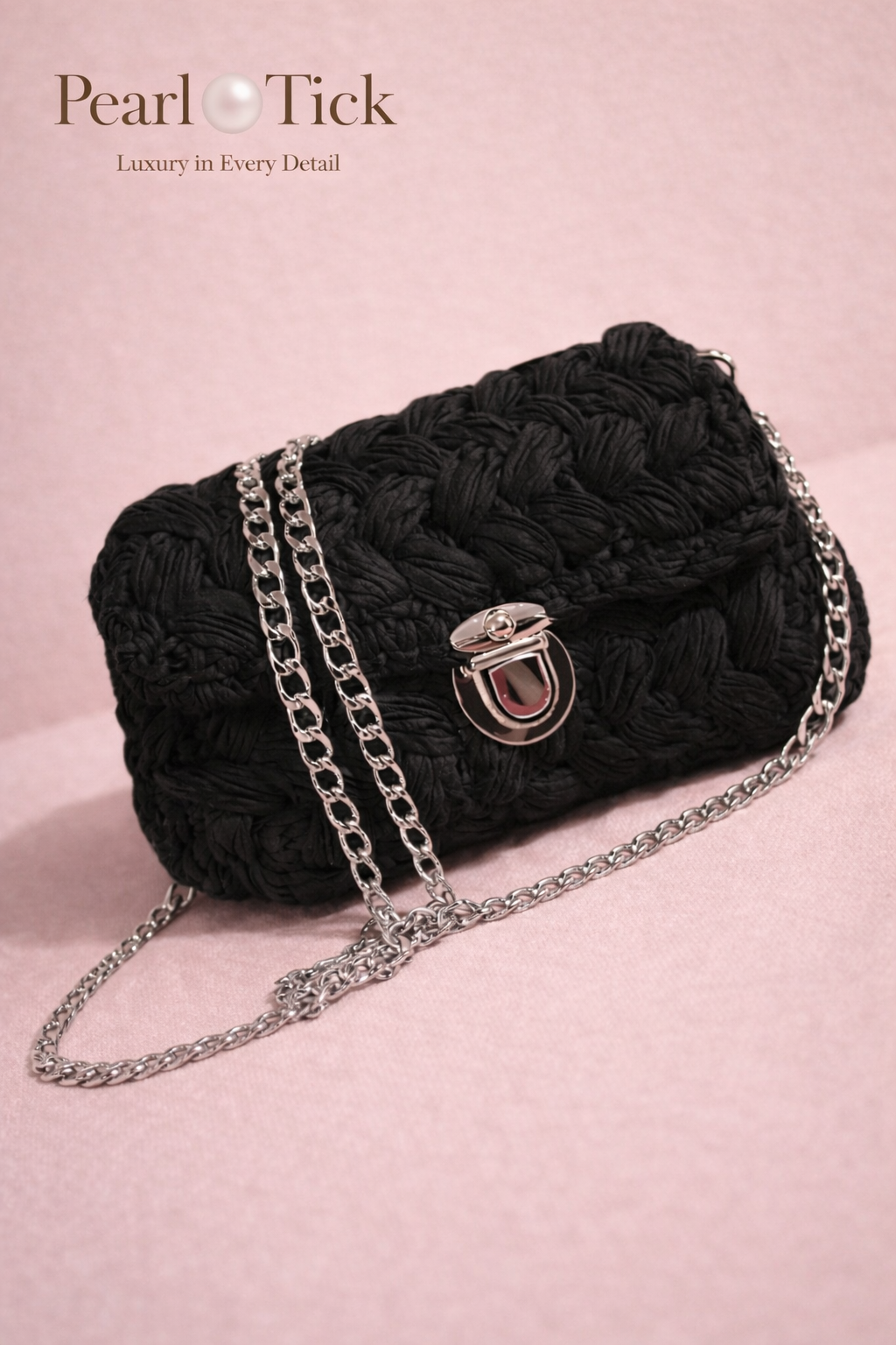 Sac à main tressé noir avec une bandoulière chaîne sur fond rose, présentant la marque 'Pearl Tick'.