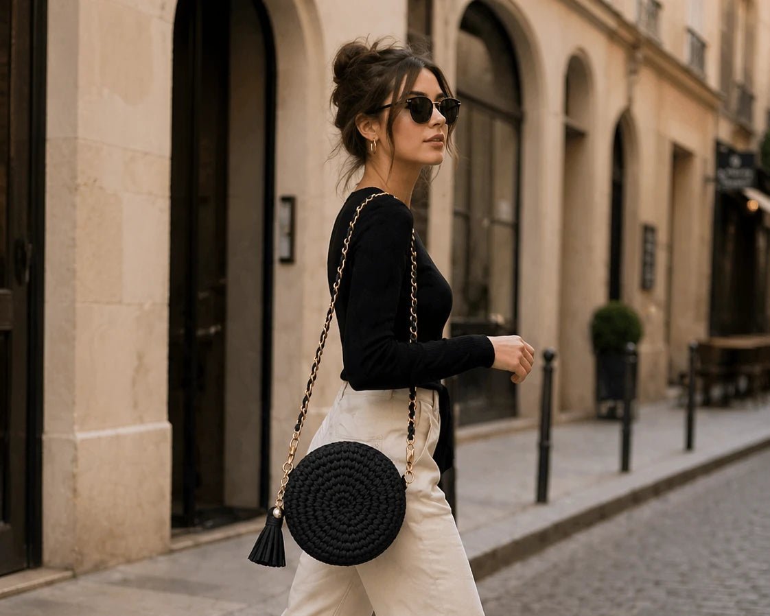 Pearl Signature Round Bag - Pearl & TickPearl Signature Round BagHandbagsPearl & TickPearl & TickPROUND-PNKPinkFashionable woman walking on an urban street wearing a black top, white pants, and white sneakers, carrying a black round handmade crochet crossbody bag with gold chain strap, modern chic style.