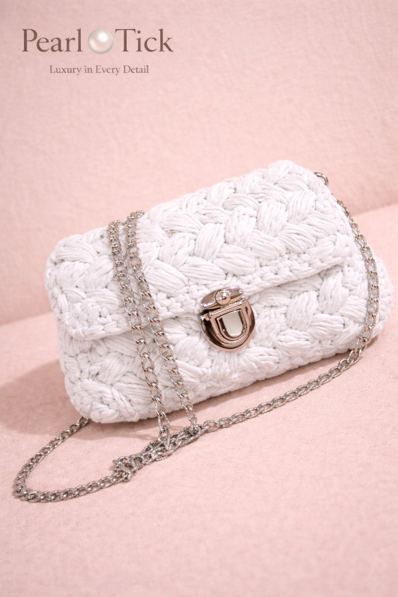 White textured handbag with chain strap on a pink background, featuring the Pearl Tick brand.