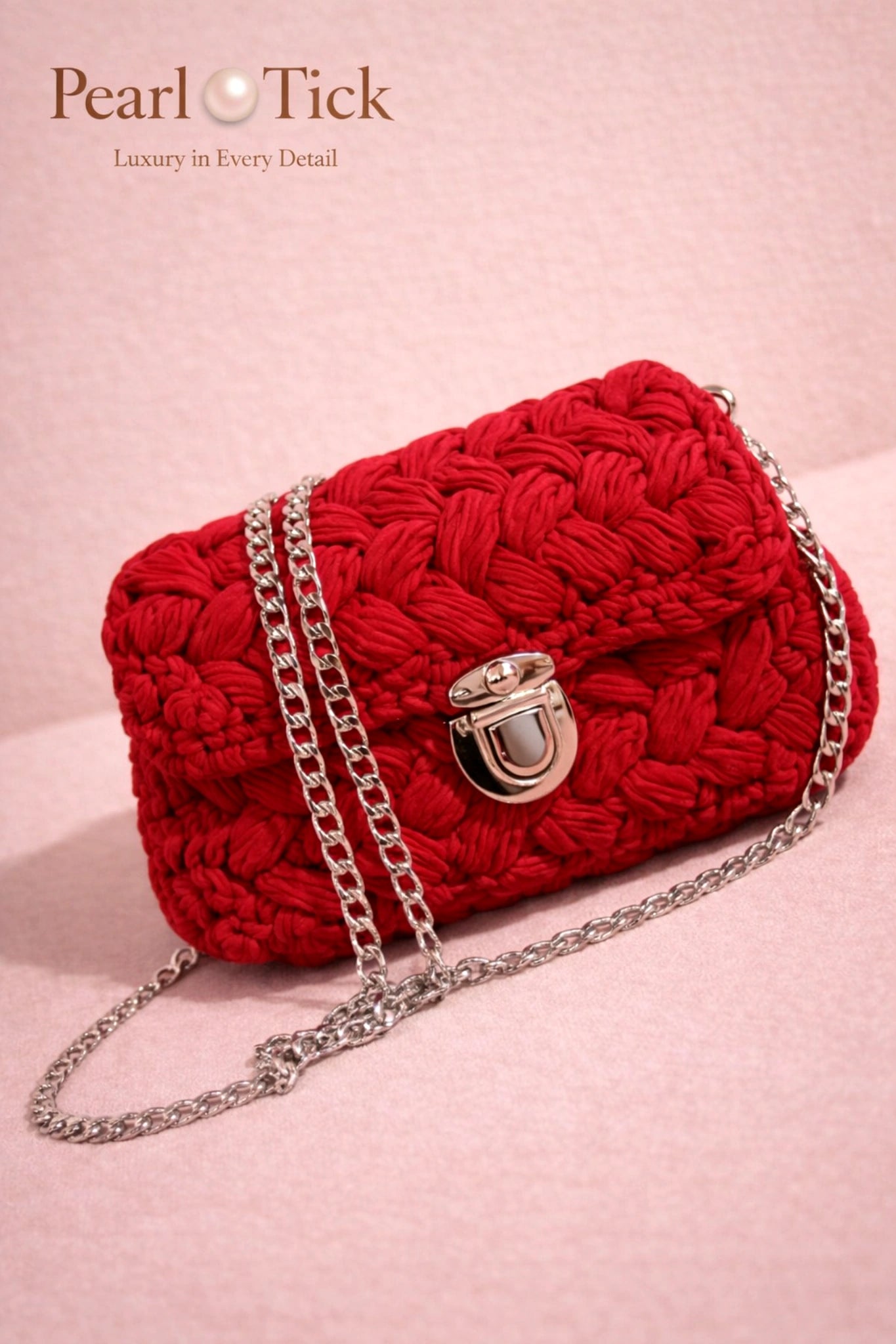 Red woven handbag with a chain strap on a pink background, featuring the Pearl Tick brand.