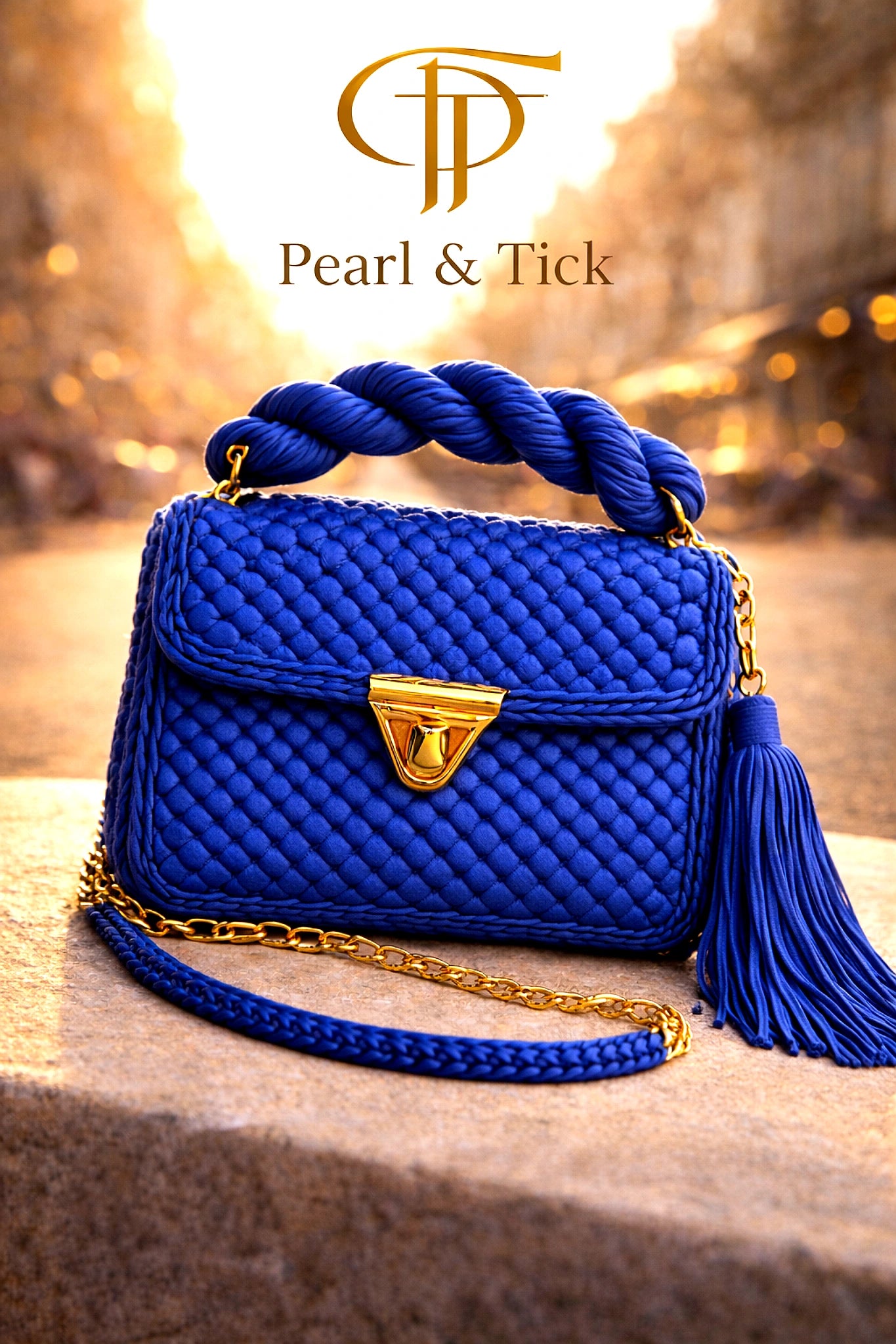 Blue quilted handbag with gold accents and a tassel on a blurred background with 'Pearl & Tick' branding.