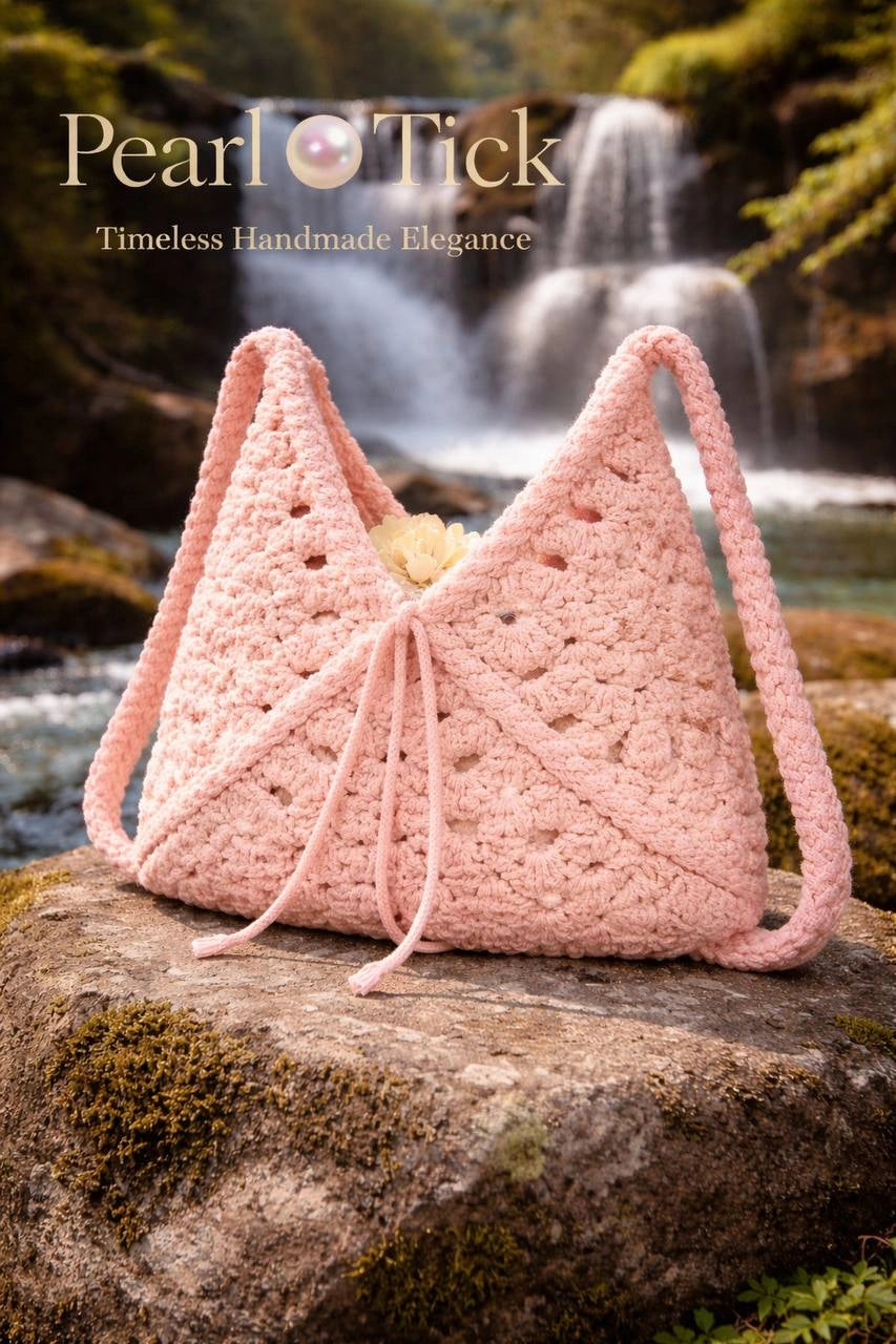 Borsa rosa all'uncinetto su una roccia con una cascata sullo sfondo, con il marchio «Pearl Tick».