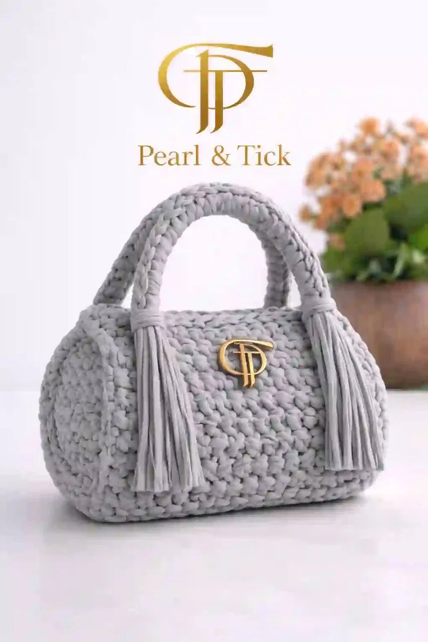 Borsa a mano grigia in tessuto con nappine e logo del marchio su sfondo bianco