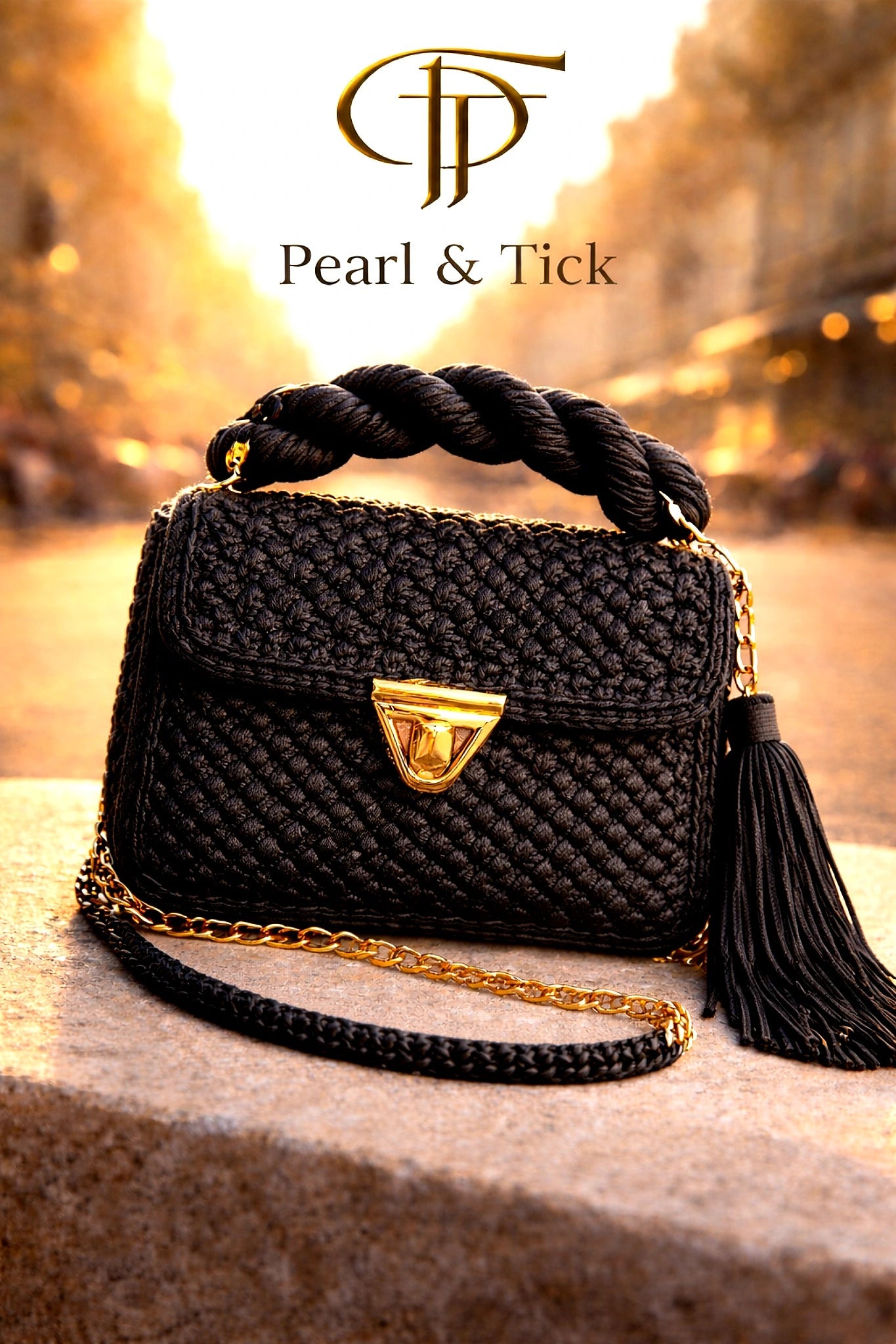 PT Golden Charm Bag - Pearl & TickPT Golden Charm BagHandbagsPearl & TickPearl & TickGOLDEN-BLKBlackBlack woven handbag with gold chain and tassel on a blurred background, featuring the brand 'Pearl & Tick'.