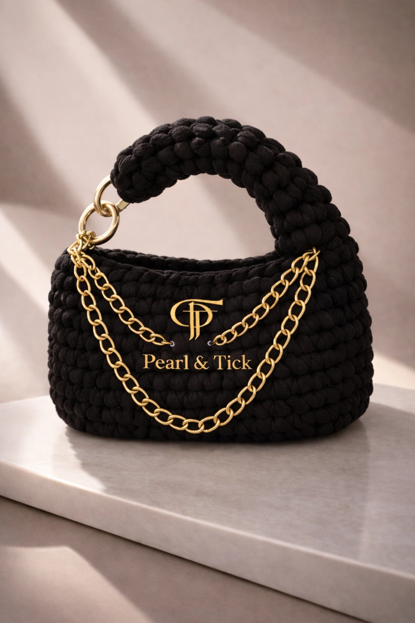 PT Knot Edition - Pearl & TickPT Knot EditionHandbagsPearl & TickPearl & TickKNOT-BLKBlackElegant Black Handbag: Features sophisticated gold chain detailing against a clean, light background. A luxurious and cinematic design that embodies the signature craftsmanship of Pearl & Tick.