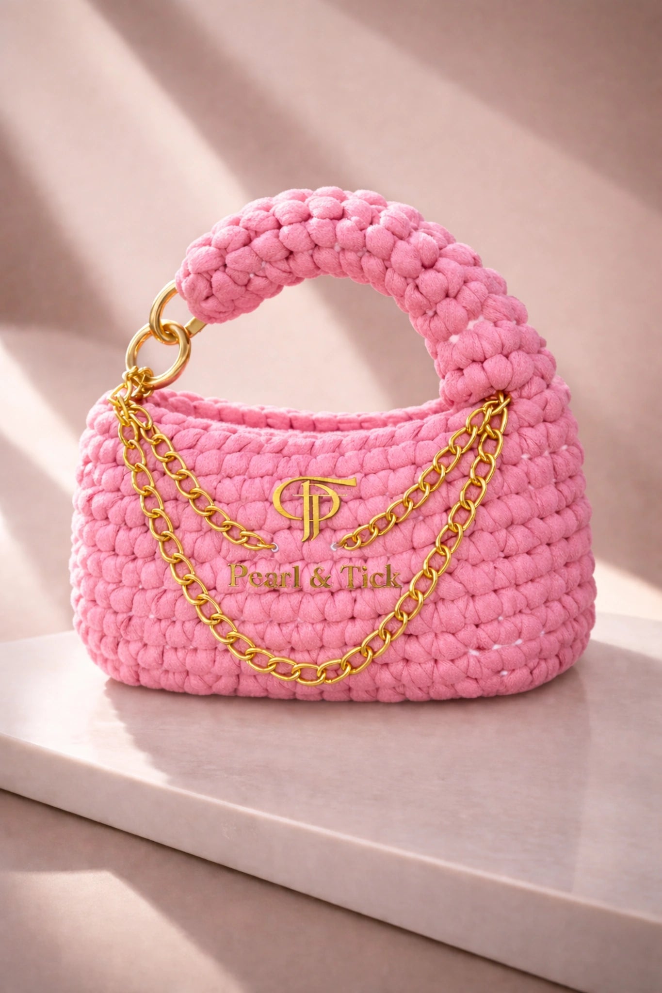 PT Knot Edition - Pearl & TickPT Knot EditionHandbagsPearl & TickPearl & TickKNOT-PNKPinkChic Pink Textured Handbag: Featuring a premium gold chain and elegant handle, beautifully showcased on a light background. A perfect blend of luxury and sophisticated craftsmanship by Pearl & Tick.