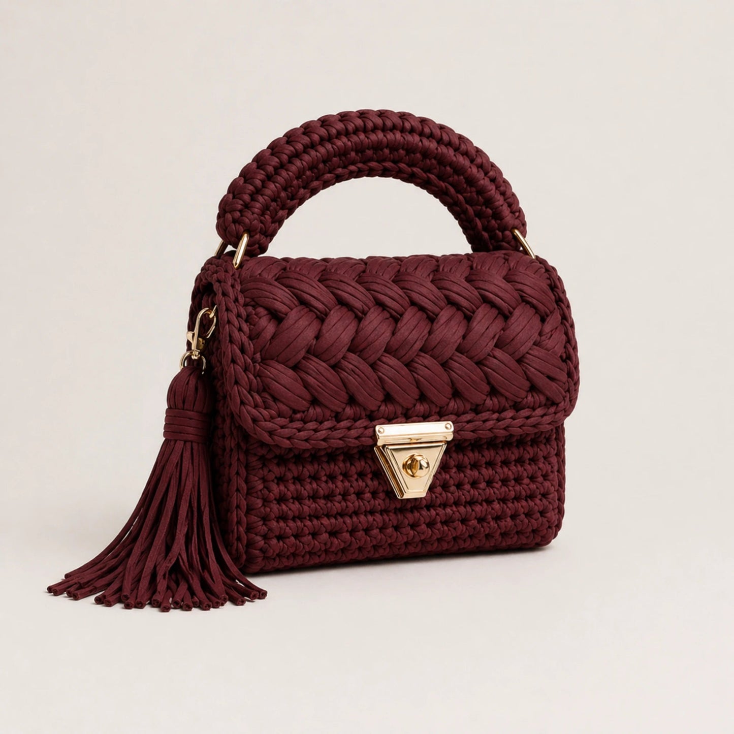Maroon woven handbag with a tassel on a light beige background